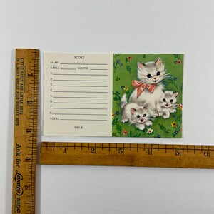 K&ouml;nnte beinhalten: Eine rechteckige Punktekarte mit den Ma&szlig;en ca. 8,25 cm mal 14 cm. Die Karte hat einen cremefarbenen Bereich mit Zeilen f&uuml;r Name, Tisch, Paar und Punkte sowie einen gr&uuml;nen Bereich mit drei K&auml;tzchen und Blumen. Der Text lautet 940-B.