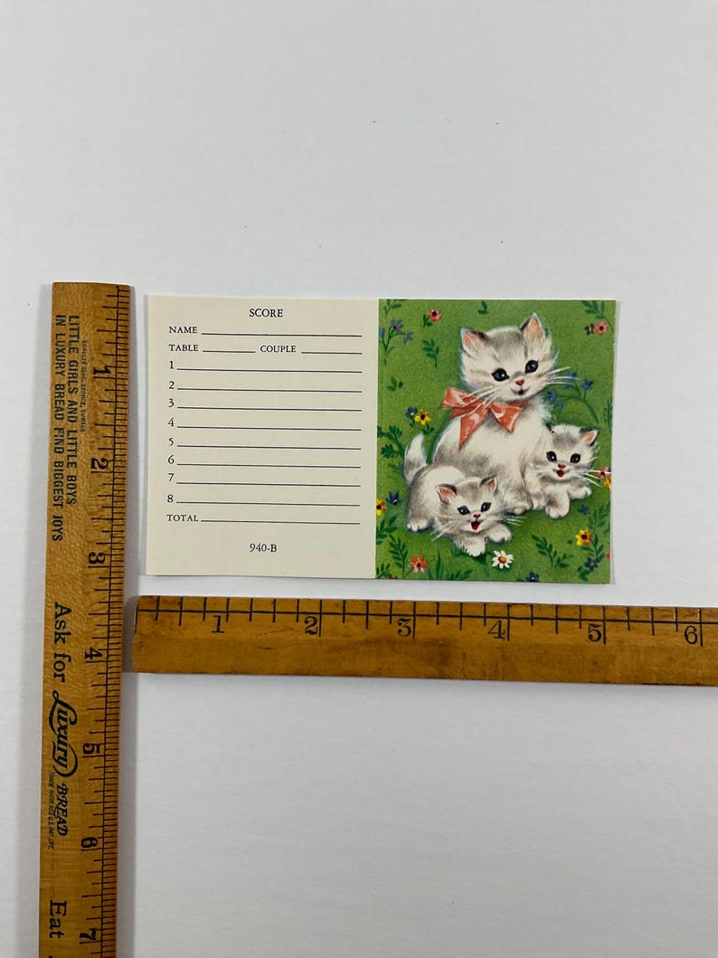 K&ouml;nnte beinhalten: Eine rechteckige Punktekarte mit den Ma&szlig;en ca. 8,25 cm mal 14 cm. Die Karte hat einen cremefarbenen Bereich mit Zeilen f&uuml;r Name, Tisch, Paar und Punkte sowie einen gr&uuml;nen Bereich mit drei K&auml;tzchen und Blumen. Der Text lautet 940-B.