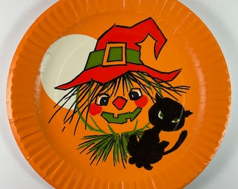 May include: Orange paper party plate with a witch and black cat illustration. The witch is wearing a red and green hat and has a pumpkin face. The cat is sitting next to the witch.