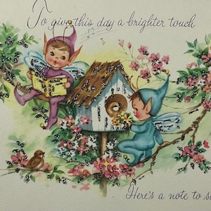 May include: A vintage-style greeting card illustration featuring two winged elves in purple and blue outfits near a birdhouse. The text reads, "To give this day a brighter touch" and "Here's a note to say-" amidst pink blossoms and green leaves.
