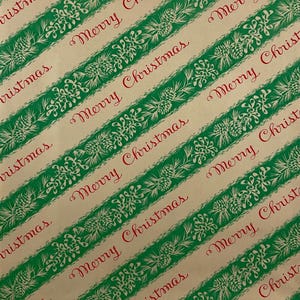 May include: Tan wrapping paper with diagonal green stripes featuring white floral and pinecone designs. The words "Merry Christmas" are written in red script across the paper, creating a festive holiday pattern.