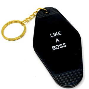 May include: Black motel key chain with a gold chain and the text "LIKE A BOSS" in white.