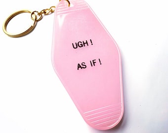 Può includere: Portachiavi in plastica rosa a forma di chiave d'albergo con un anello dorato. Il portachiavi ha la scritta "UGH! AS IF!" stampata su di esso.