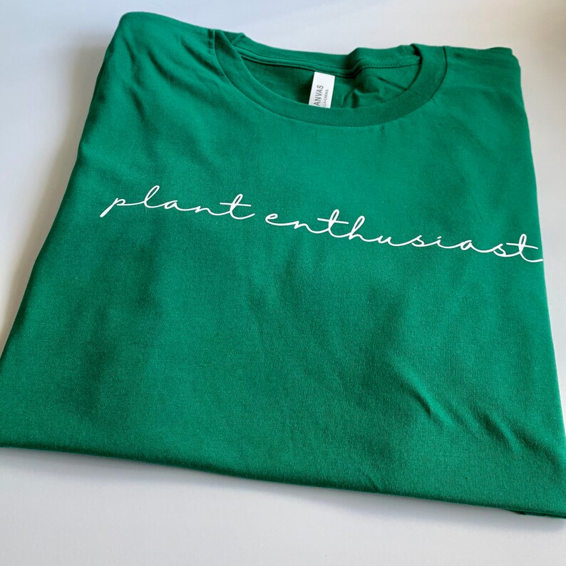 May include: A green t-shirt with the text "plant enthusiast" written in white cursive.