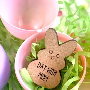 May include: A wooden bunny-shaped Easter egg with the text "Day with Mom" inside a pink plastic Easter egg with green shredded paper.