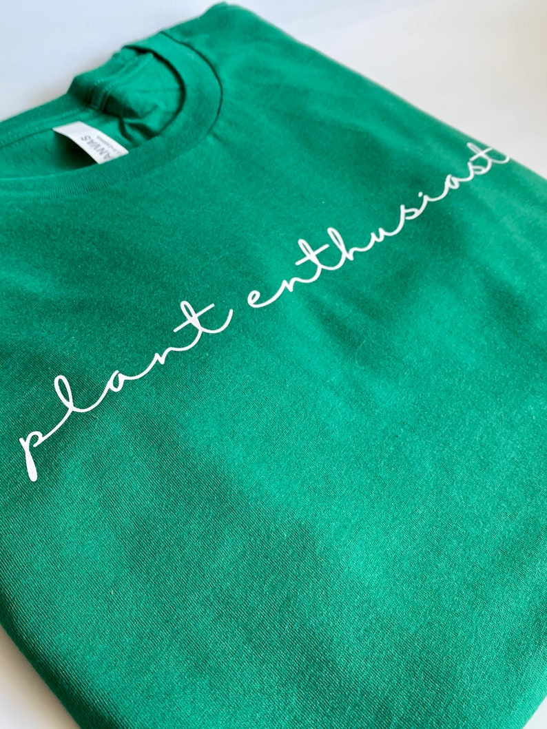 May include: A green t-shirt with the text "plant enthusiast" written in white cursive.