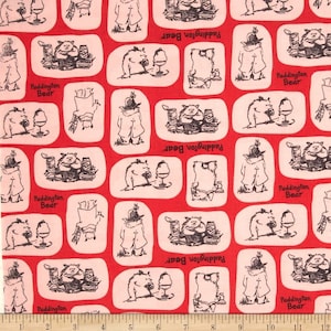 May include: Red fabric with a repeating pattern of Paddington Bear illustrations. The illustrations show Paddington Bear in various poses, including holding a jar of marmalade, reading a book, and drinking tea. The text "Paddington Bear" is repeated throughout the fabric.
