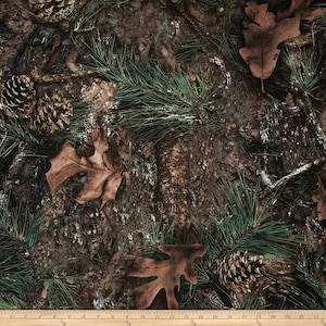 May include: Camouflage fabric with a brown, green, and white pattern featuring pine needles, leaves, and pine cones.