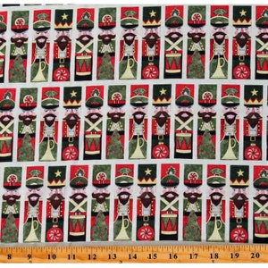 May include: Christmas-themed fabric featuring a repeating pattern of toy soldiers. The soldiers are depicted in red, green, and black uniforms with gold accents. Each soldier holds a drum, trumpet, or ornament. The background is off-white.