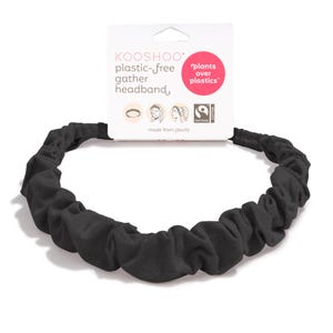 May include: A black, gathered headband made from plants. The headband is plastic-free and features the text "KOOSHOO plastic-free gather headband" on the attached tag. The tag also includes the phrase "plants over plastics."