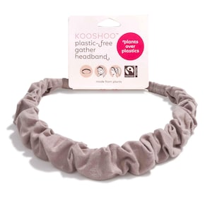 May include: A light brown, plastic-free headband with a gathered design. The headband is made from plants and has a tag that reads "KOOSHOO plastic-free gather headband" with the words "plants over plastics".