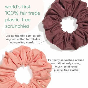May include: Two fabric scrunchies, one in a light pink color and one in a dark burgundy color. The scrunchies are made from organic cotton and are plastic-free. The text "KOOSHOO" is printed on the burgundy scrunchie.