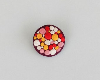 Brooch with colorful beaded embroidery on purple background