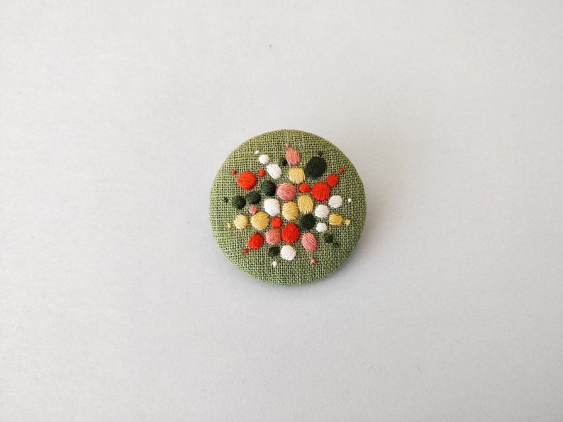 Brooch with embroidery style colored pearls on a light green background image 1