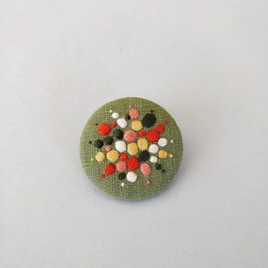 Brooch with embroidery style colored pearls on a light green background image 6