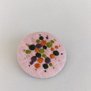 Brooch with embroidery style colored pearls on pink background image 2