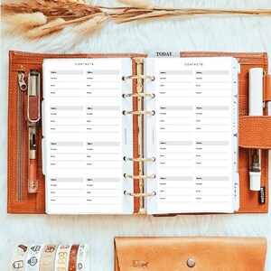 May include: A brown leather planner with gold rings and white pages. The pages are divided into sections labelled "Contacts" and "Today". The planner is open to a page with a contact list.