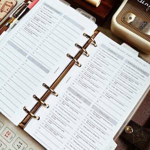 May include: An open planner with gold rings and lined pages. The planner includes checklists for party/event preparation, with sections for planning, setup, and event day tasks. Pens and a vintage radio are in the background.