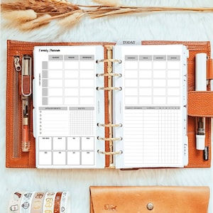 May include: A white family planner with a gold binder. The planner has sections for appointments, notes, and a weekly calendar. The planner also has a section for daily tasks and a section for family members and chores.