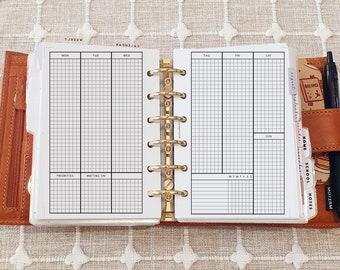 May include: A tan leather ring-bound planner featuring a gold six-ring mechanism and white grid-lined weekly calendar inserts. The pages include headers for days of the week, a priorities section, a waiting on section, and labeled monthly divider tabs.