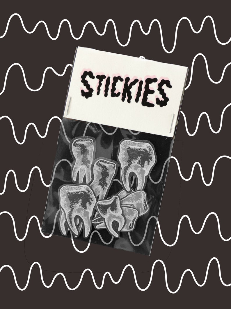 May include: A clear plastic bag with the word "STICKIES" printed on the front. The bag contains a set of black and white tooth-shaped stickers.
