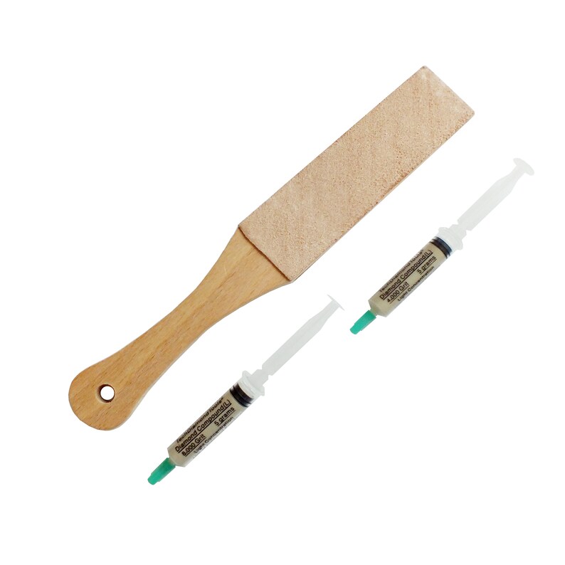 May include: A wooden handled strop with a tan leather surface, and two syringes of diamond compound. The syringes have white barrels, green tips, and text that reads "Diamond Compound (L) 5.000 Grit 5 grams".