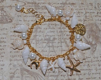 Pulseira com pingentes Mermaidcore • Conchas brancas e pérolas artificiais • Tartaruga e estrela-do-mar Howlita • Dólar-de-areia, estrela-do-mar e golfinho banhados a ouro 18K