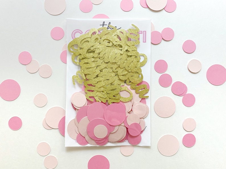 K&ouml;nnte beinhalten: Goldenes Konfetti mit dem Wort "Confetti" in goldenen Glitzerbuchstaben, umgeben von rosa und hellrosa Konfetti-Kreisen.