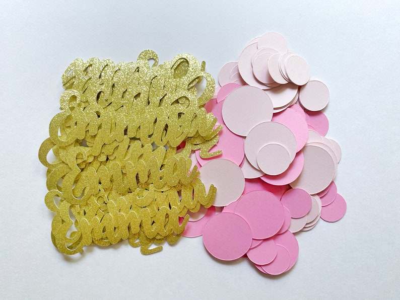 K&ouml;nnte beinhalten: Goldener Glitzerkonfetti mit den Worten "Happy Birthday" und rosa Konfetti-Kreisen.