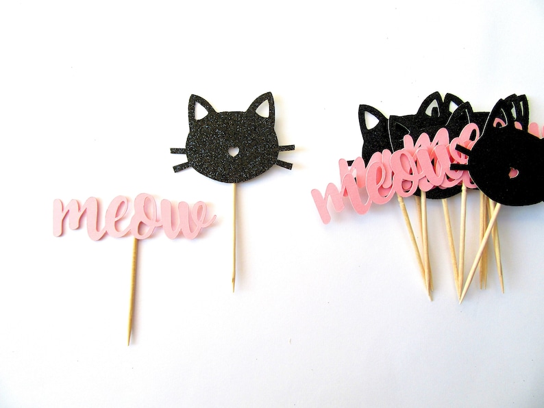 Puede incluir: Toppers para cupcakes de papel rosa y negro con la palabra "miau" y siluetas de gatos negros.