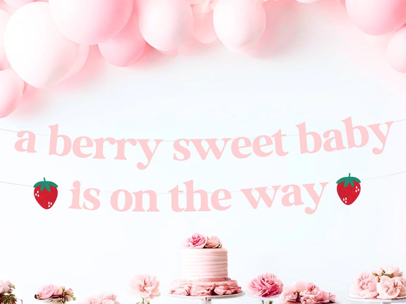May include: A pink banner with the text "a berry sweet baby is on the way" and strawberry illustrations. Pink balloons are in the background, with a cake and flowers on a table below.