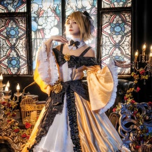 Può includere: Una donna in costume cosplay con un abito giallo, nero e bianco. L'abito presenta maniche scoperte, un fiocco nero e dettagli dorati. Lo sfondo include vetrate e elementi decorativi.