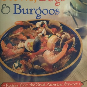 Pode incluir: Um livro de receitas intitulado "Stews, Bogs & Burgoo's: Recipes from the Great American Stewpot" de James Villas. A capa apresenta um close-up de uma tigela de ensopado de frutos do mar com camarão, amêijoas e vegetais.