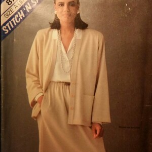 May include: A vintage sewing pattern cover featuring a woman wearing a beige skirt suit. The suit includes a long jacket with pockets and a matching skirt. The pattern is labeled "Stitch 'N Save" and size A (10-12).