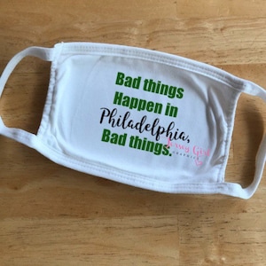 May include: White face mask with the text "Bad things happen in Philadelphia, Bad things." in green text. The text "Jersey Girl Graphics" is also in green text.