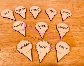 May include: Wooden cheese markers with different cheese names written on them, including gouda, mozzarella, mild, colby, sharp, muenster, aged, smoked, cheddar, havarti, and gruyere.