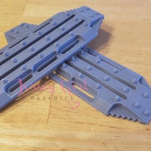 May include: Two gray plastic traction mats with raised studs and grooves. The mats are designed to help vehicles gain traction on slippery surfaces.