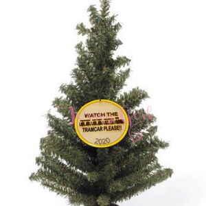 Puede incluir: Un peque&ntilde;o &aacute;rbol de Navidad artificial con un adorno redondo amarillo que dice "Watch the Tramcar Please!" y "2020".