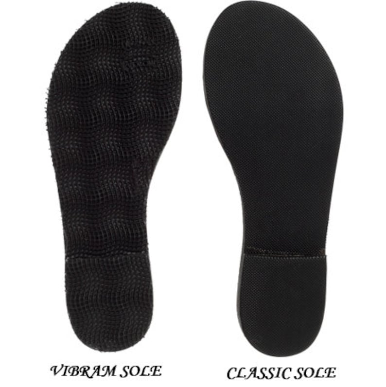 May include: Two black shoe soles are displayed side-by-side against a white background. The left sole is labeled "VIBRAM SOLE" and has a textured, grid-like pattern. The right sole, labeled "CLASSIC SOLE", has a smooth, slightly textured surface.