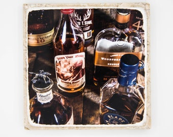 May include: A close-up of a collection of various liquor bottles, including a bottle of Evan Williams Bottled-in-Bond Bourbon, a bottle of Woodford Reserve Double Oaked Bourbon, a bottle of  Woodford Reserve Bourbon, a bottle of  Evan Williams Bottled-in-Bond Bourbon, and a bottle of  Evan Williams Bottled-in-Bond Bourbon. The bottles are arranged on a wooden surface.