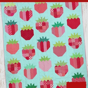 Puede incluir: Un patrón de edredón titulado The Tipsy Needle Strawberry Patch Quilt Pattern # TTN- 129 de Sew Chic Fabric. El edredón presenta un fondo azul claro con motivos de fresas repetidos en varios patrones de tela rojos y rosas con hojas verdes.