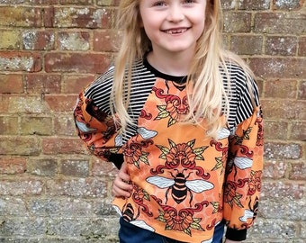 Organic bee dolman tshirt for babies and kids, handmade in the UK. Black stripe, colour blocked bishop sleeve tshirt with bee print