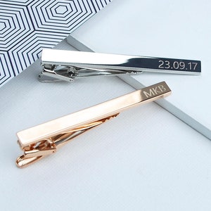Personalised tie clip shown in silver(rhodium plated) and rose gold plated finishes with engraved initials and a date.