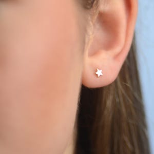 May include: A close-up of a person's ear with a small silver star stud earring.