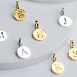 Sterling Silver and Gold plated sterling silver initial letter disc charms shown close up.