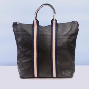 May include: A black leather tote bag with navy blue and white striped handles.