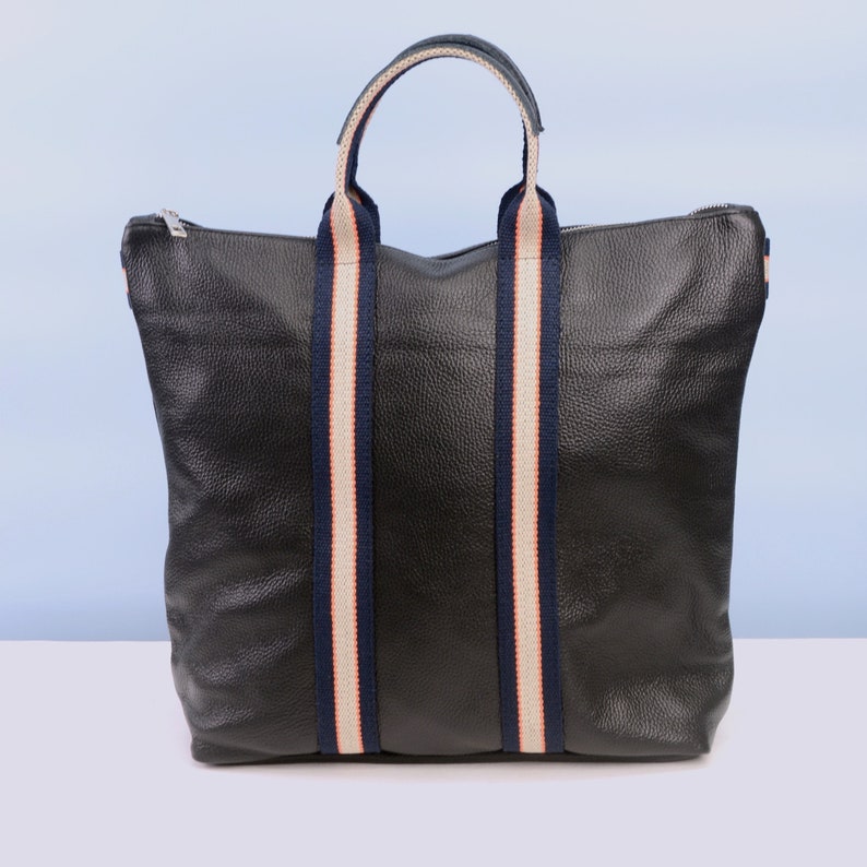 May include: A black leather tote bag with navy blue and white striped handles.