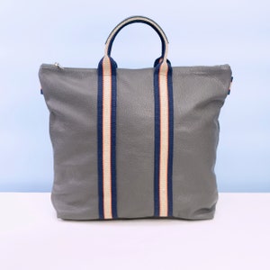 May include: A grey leather tote bag with navy blue and white striped straps.