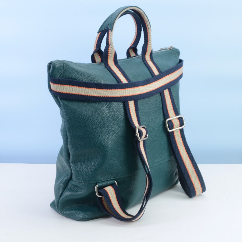May include: A teal leather backpack with white and navy blue striped straps. The straps are adjustable and have a buckle closure.