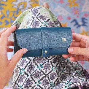 Teal Personalised Leather Glasses case shown close up with model with JB monogram in gold.